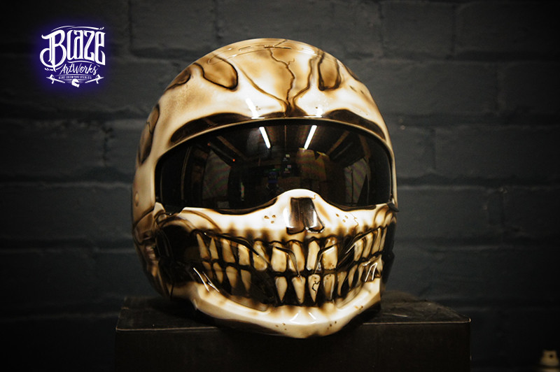 Gothic skull motorcycle helmet with cream and brown airbrush paint job featuring detailed jaw bones and teeth on black visor